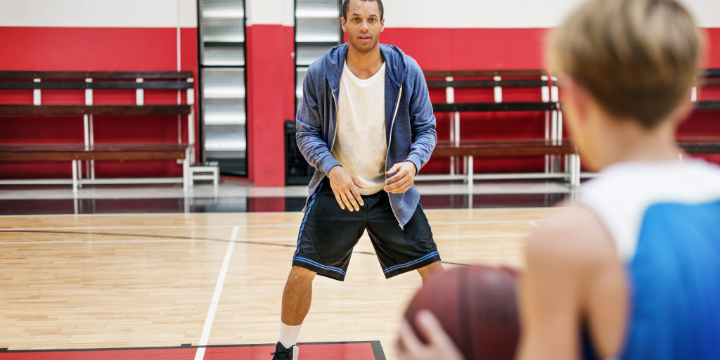 coach teaching a player to shoot ball