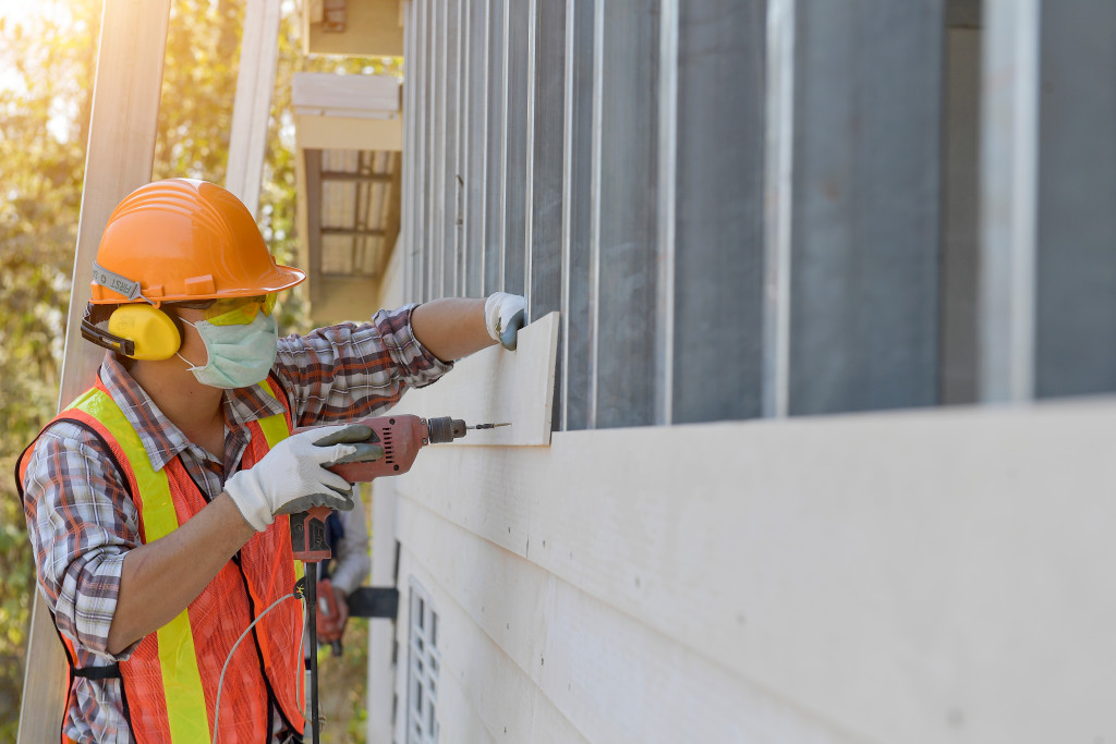 male contractor adding siding for home construction